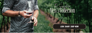 Man holding a glass of red wine in a vineyard with 'The Signature Men's Collection' text overlay.